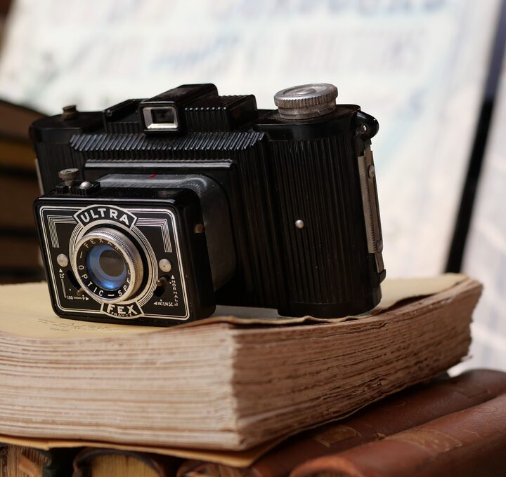 Cámara fotográfica analógica antigua sobre un montón de libros y documentos encuadernados